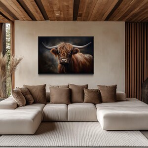 a large, white sectional sofa with brown throw pillows, positioned in front of a large window that offers a view of trees. Above the sofa, there is a framed painting of a cow with horns.