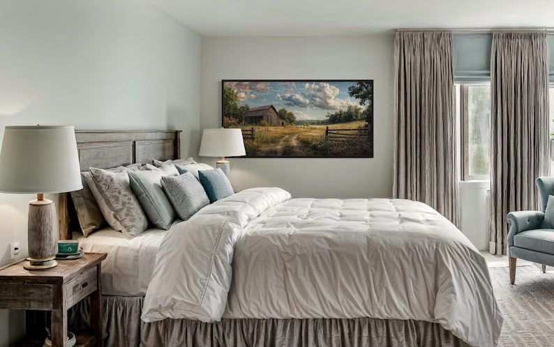 a serene bedroom with a large bed, a wooden headboard, and a painting of a rural landscape hanging on the wall. The room has a neutral color scheme with gray curtains and a white comforter on the bed.