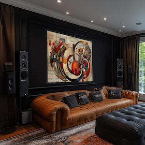 a modern living room with a large abstract painting on the wall, a brown leather sofa, a black ottoman, and a large window overlooking trees.