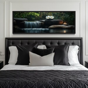 a serene bedroom scene with a large bed adorned with black and white bedding, flanked by two black nightstands. Above the bed, a framed picture of a waterfall and a flower is displayed, creating a calming and peaceful atmosphere.
