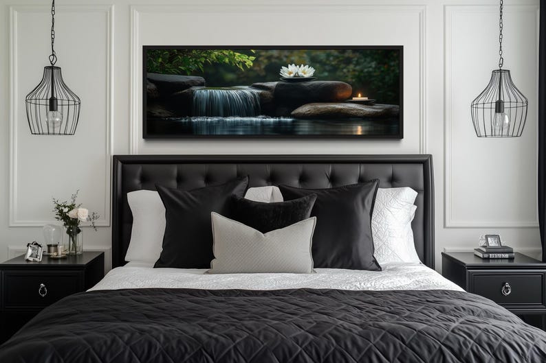 a serene bedroom scene with a large bed adorned with black and white bedding, flanked by two black nightstands. Above the bed, a framed picture of a waterfall and a flower is displayed, creating a calming and peaceful atmosphere.