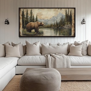 a large painting of a bear in a forest setting, hanging on a wall above a white sectional sofa in a living room.