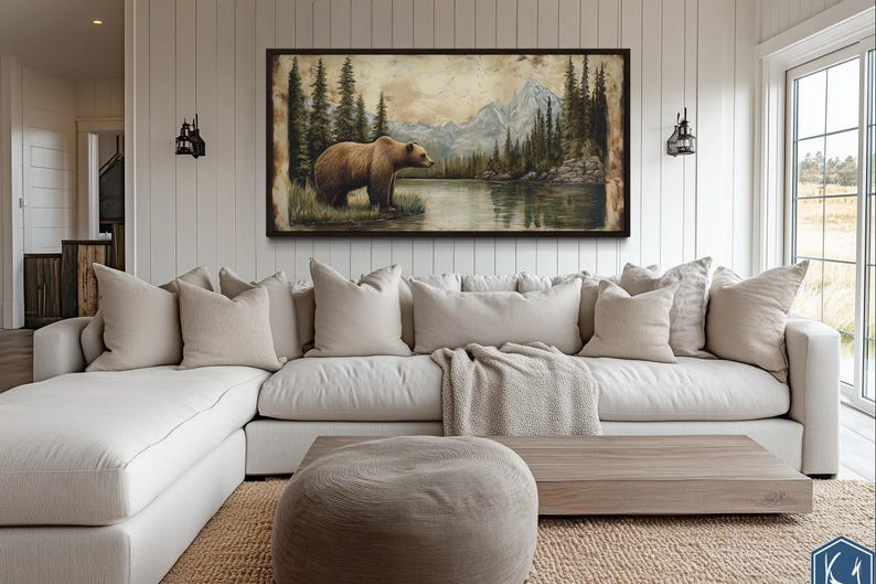a large painting of a bear in a forest setting, hanging on a wall above a white sectional sofa in a living room.