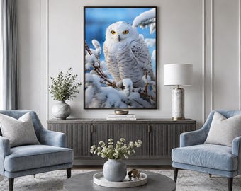 May include: A framed wall art print featuring a snowy owl with bright yellow eyes perched on a snow-covered pine branch against a soft blue background, displayed in a living room setting with two light blue armchairs and a grey sideboard.