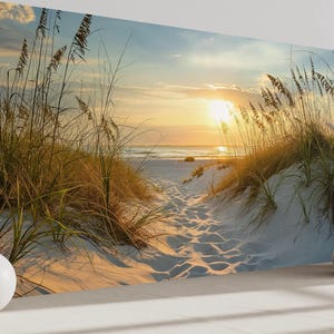 a serene beach scene with tall grasses swaying in the foreground and a path leading to the beach in the distance, with the sun setting over the horizon.