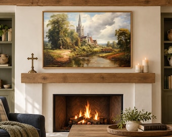 May include: A framed landscape painting depicting a church with a tall spire situated near a river, surrounded by lush green trees and a cloudy sky. The artwork is displayed above a fireplace mantel with a burning fire in the hearth below.
