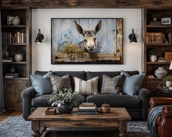 May include: A rectangular wall art print featuring a donkey peering over a rustic wooden fence against a light blue plank background, accented with small orange and blue flowers, displayed in a black frame above a dark gray sofa in a room.