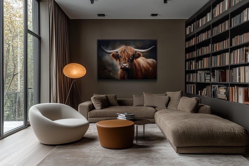 a modern living room with a large window overlooking trees, a comfortable sofa, a round coffee table, and a large painting of a horned animal on the wall.