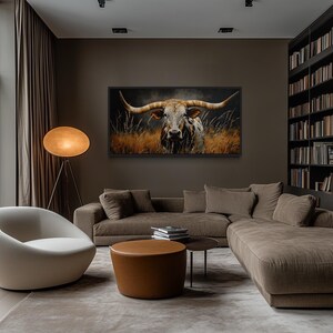 a modern living room with a large window overlooking trees, a comfortable sofa, a round coffee table, and a large painting of a bull's head on the wall.