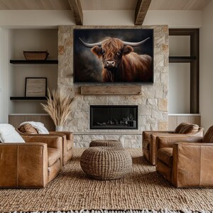 a modern living room with a large stone fireplace, a large window, and a framed painting of a bull's head hanging above the fireplace. The room is furnished with brown leather sofas and chairs, and the overall decor has a rustic, natural aesthetic.