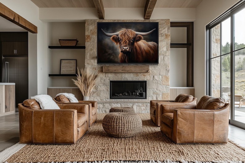 a modern living room with a large stone fireplace, a large window, and a framed painting of a bull's head hanging above the fireplace. The room is furnished with brown leather sofas and chairs, and the overall decor has a rustic, natural aesthetic.