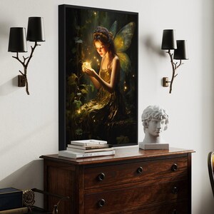 a large painting of a fairy with a glowing lantern in her hand, displayed on a wall above a wooden dresser. The dresser has a white bust and a stack of books on top. The room has a window with trees visible outside, and there are two black lamps on the wall.