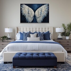 a well-decorated bedroom with a large bed, a tufted headboard, and a blue tufted ottoman. Above the bed is a large painting of white wings. The room also features a nightstand on each side of the bed, with a lamp and a plant. The walls are painted in a light color, and the floor is covered with a blue and white patterned rug.