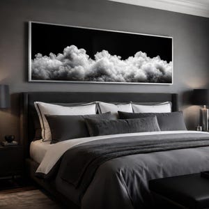 May include: A modern bedroom with a dark gray color scheme. A large framed artwork depicting white clouds against a black background hangs above a bed with gray bedding and pillows. Black lamps and a bench complete the room's elegant design.