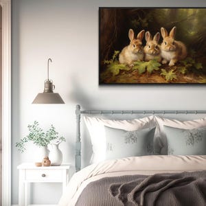 a cozy bedroom scene with a bed, a nightstand, and a painting of three rabbits on the wall.
