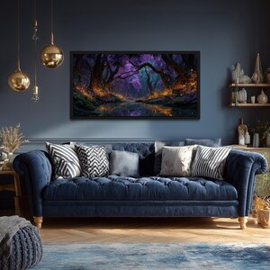Op de afbeelding: Een donkerblauwe bank met kussens staat tegen een donkerblauwe muur. Boven de bank hangt een ingelijst landschapsschilderij met een bossc&egrave;ne in paarse en oranje tinten. Gouden hanglampen hangen aan het plafond.