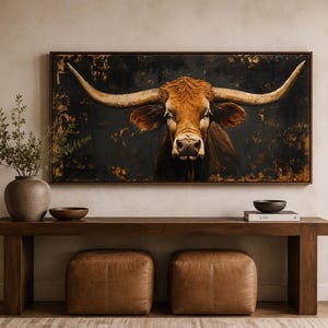 May include: A rectangular wall art piece featuring a detailed portrait of a longhorn steer with prominent horns, set against a dark, textured background with gold accents. The artwork is framed in a thin, dark wood border and displayed horizontally.