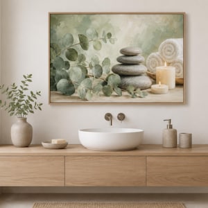 May include: A rectangular framed wall art print featuring a stack of four smooth grey stones, a sprig of green eucalyptus leaves, two lit cylindrical candles, and three rolled white towels against a soft, muted green and beige background.
