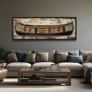 May include: A framed rectangular wall art featuring a rustic canoe design. The canoe is painted in shades of black, brown, and beige, with colorful diamond patterns. The artwork hangs above a beige sectional sofa in a living room setting.