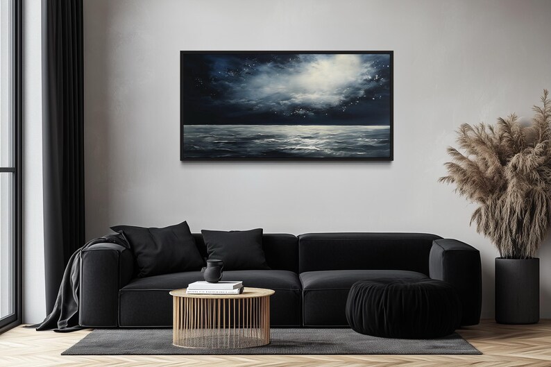 a modern living room with a black sofa, a wooden coffee table, and a large painting of a stormy ocean scene hanging on the wall above the sofa.