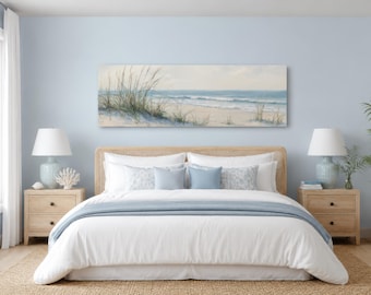 Peut inclure: Une peinture paysagère rectangulaire représentant une plage avec des dunes de sable, de hautes herbes et des vagues bleues, suspendue au-dessus d'un lit avec une parure blanche, un jeté bleu clair et deux lampes de chevet assorties.