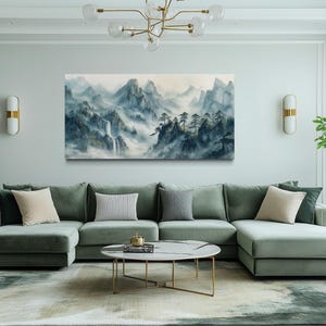 a modern living room with a large green sectional sofa, a round coffee table, and a painting of a mountainous landscape hanging on the wall.