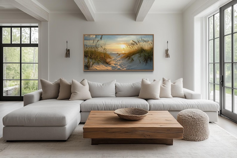 a modern living room with a large window overlooking a beach, a wooden coffee table, and a comfortable sectional sofa with throw pillows.