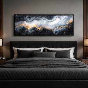 May include: A modern bedroom featuring a large abstract art piece above a bed. The artwork has a black frame and depicts a swirling pattern of white, gold, and black. The bed is covered in dark gray bedding, with matching pillows.
