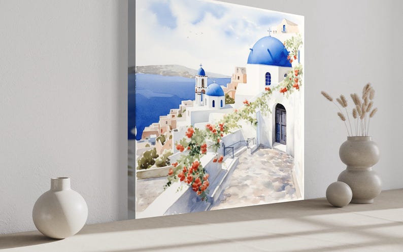 a large painting of a picturesque Greek island with white buildings, blue domes, and a blue sky with clouds. The painting is displayed on a wall, and there are two white vases and a small white sculpture placed in front of it.