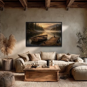 May include: A framed landscape painting depicts a serene lake scene with a wooden boat tied to a dock. The artwork features a misty atmosphere, with trees and mountains in the background. The color palette includes warm tones of brown, beige, and gold.