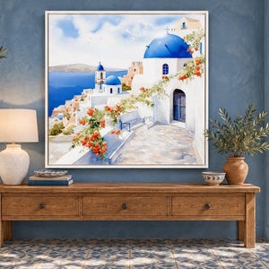 May include: A square framed wall art print depicting a Mediterranean coastal scene with white buildings, bright blue domes, and vibrant orange flowers. The painting features a stone pathway leading toward the sea under a clear blue sky.