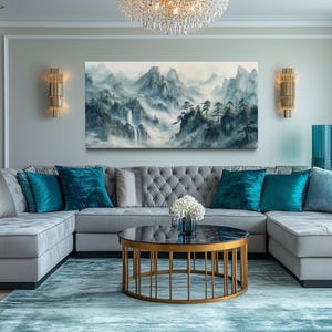 a modern living room with a gray sectional sofa adorned with blue throw pillows, a round coffee table with a gold base, and a large landscape painting on the wall. The room is decorated with gold accents and a chandelier, creating a luxurious and sophisticated atmosphere.