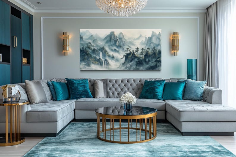 a modern living room with a gray sectional sofa adorned with blue throw pillows, a round coffee table with a gold base, and a large landscape painting on the wall. The room is decorated with gold accents and a chandelier, creating a luxurious and sophisticated atmosphere.