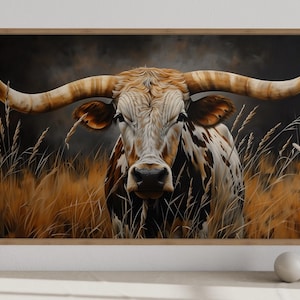 a large painting of a bull with long horns, set against a backdrop of tall grass and wildflowers. The bull is the central focus of the painting, with its horns prominently displayed. The painting is framed and hung on a wall, with a few decorative objects placed in front of it.