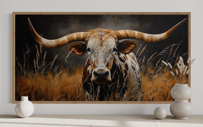 a large painting of a bull with long horns, set against a backdrop of tall grass and wildflowers. The bull is the central focus of the painting, with its horns prominently displayed. The painting is framed and hung on a wall, with a few decorative objects placed in front of it.