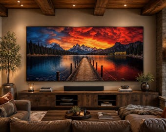May include: A large rectangular wall-mounted television displaying a vibrant landscape of a wooden pier extending into a lake toward snow-capped mountains under a dramatic sunset sky with deep orange, red, and blue clouds in a living room.