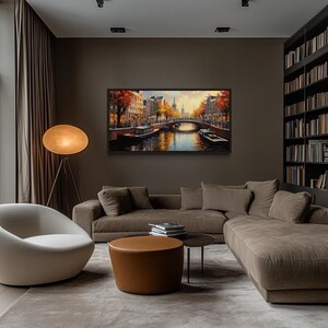 a modern living room with a large window overlooking a scenic view of a canal and trees. The room features a comfortable sofa, a round coffee table, and a floor lamp, creating a cozy and inviting atmosphere. A large bookshelf filled with books adds a touch of intellectual charm to the space. The room is illuminated by natural light from the window, enhancing the overall ambiance.