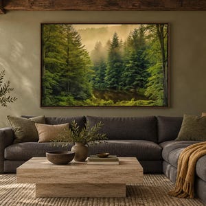 May include: A large rectangular framed wall art print depicting a dense green forest with tall pine trees and misty fog over a calm body of water, mounted on a solid olive green wall above a dark gray sectional sofa with textured pillows.