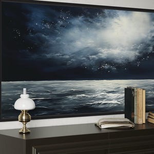 a large painting of a stormy ocean scene, with a dark sky and white clouds, as well as a lamp and a stack of books on a dresser.