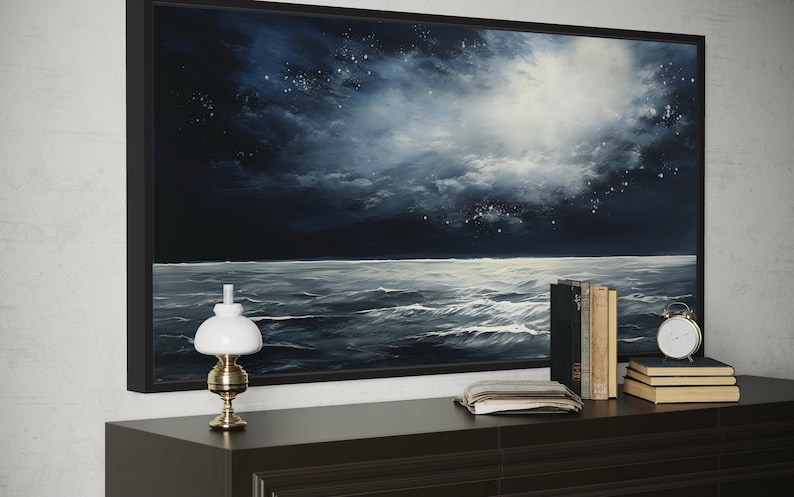 a large painting of a stormy ocean scene, with a dark sky and white clouds, as well as a lamp and a stack of books on a dresser.