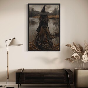 a large framed artwork depicting a witch standing in a field, with a body of water in the background. The artwork is hanging on a wall above a wooden bench.