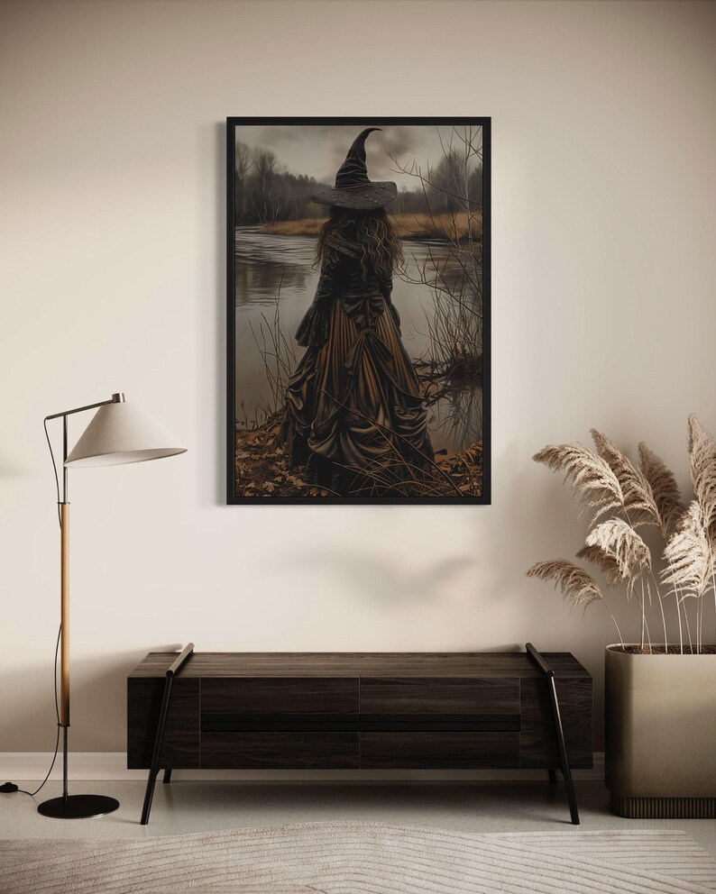 a large framed artwork depicting a witch standing in a field, with a body of water in the background. The artwork is hanging on a wall above a wooden bench.