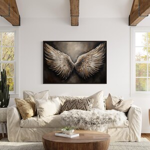 a cozy living room with a large window, a white sofa, a wooden coffee table, and a framed artwork of a pair of large, outstretched wings hanging on the wall.
