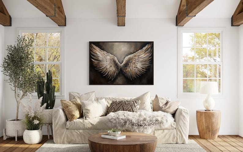 a cozy living room with a large window, a white sofa, a wooden coffee table, and a framed artwork of a pair of large, outstretched wings hanging on the wall.