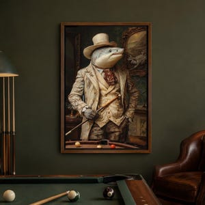 Op de afbeelding: Een ingelijste kunstdruk van een haai met een menselijk lichaam, gekleed in een beige hoge hoed, een das met patroon en een beige colbert met textuur. De haai houdt een houten biljartkeu vast bij een biljarttafel met gekleurde ballen.