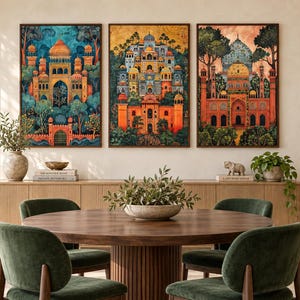May include: Three framed rectangular wall art prints featuring detailed illustrations of ornate palaces with domes and arches, set against lush green trees and foliage, displayed in a row above a wooden sideboard in a dining room.