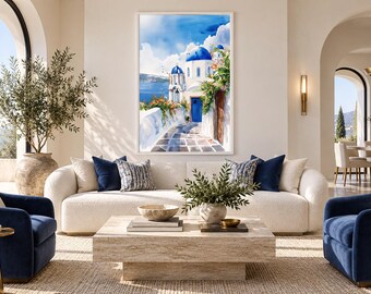 May include: A framed vertical wall art print depicting a sunlit Greek island street scene with white buildings, iconic blue domes, a vibrant blue door, and colorful flowers, displayed in a bright living room above a cream-colored sofa.