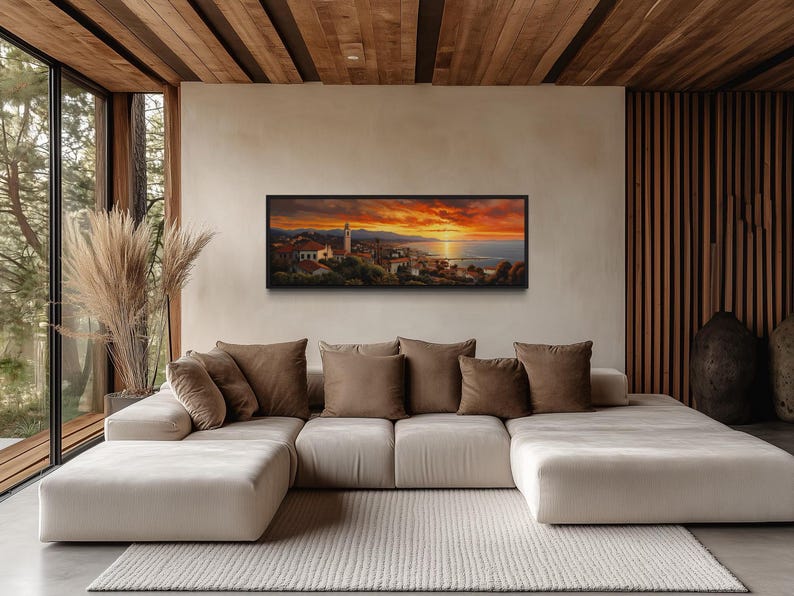 a modern living room with a large white sectional sofa, a wooden coffee table, and a large window overlooking a scenic view of a town at sunset.