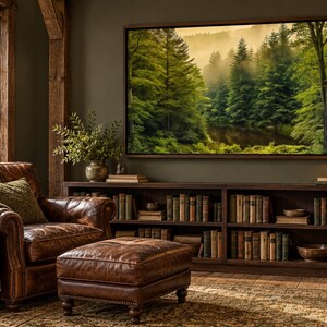 May include: A brown leather armchair with a matching ottoman, a dark wood bookshelf filled with books, and a large framed landscape painting of a misty green forest hanging on a dark olive wall next to a window and a brass desk lamp.