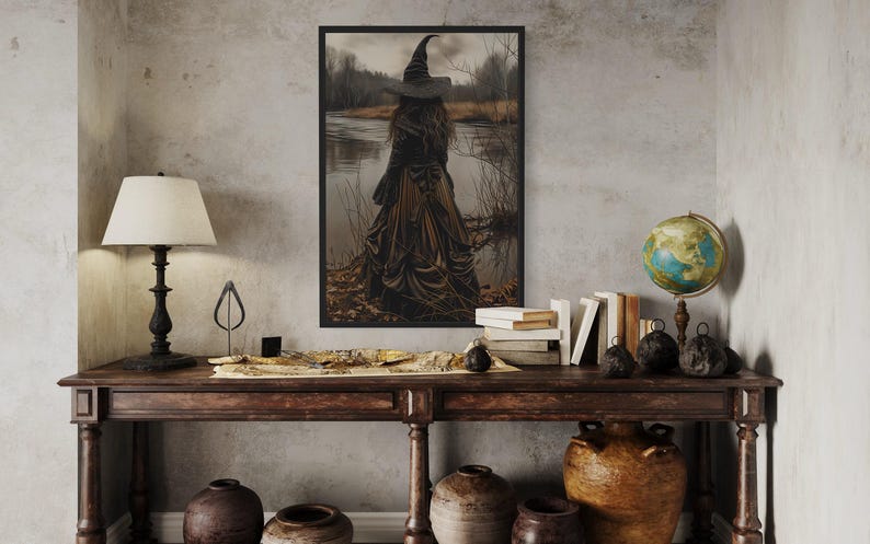 a dark-themed room with a large framed picture of a witch standing in a field, a wooden table with various knick-knacks, and a globe on top.
